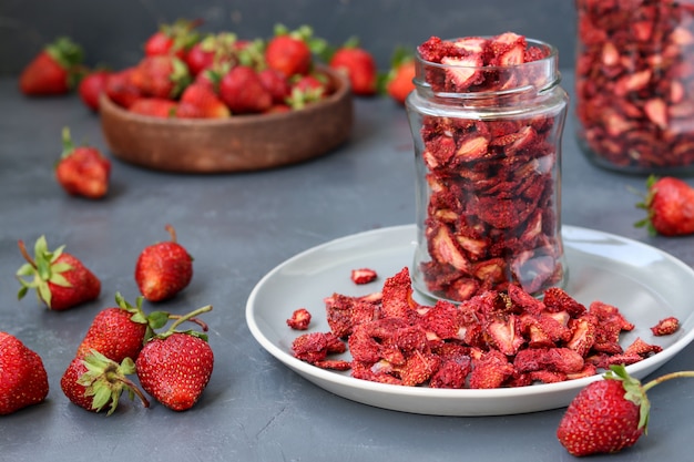 Los chips de fresa están en un frasco de vidrio sobre una superficie oscura, comida saludable