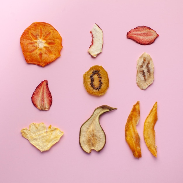 Chips de frutas secas de plátano naranja otros sobre un fondo rosa concepto de merienda saludable postre para verduras ...