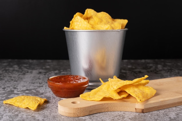 Chips de maíz mexicanos en un balde de metal y sobre una tabla de madera Enfoque selectivo en chips en la mesa