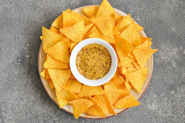 Chips de maíz con mostaza en un plato sobre un fondo gris Vista superior Espacio de copia