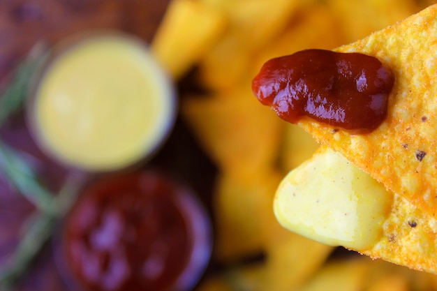 Chips de maíz Nachos aislados con salsa, llevados a la boca, vista superior con fondo borroso