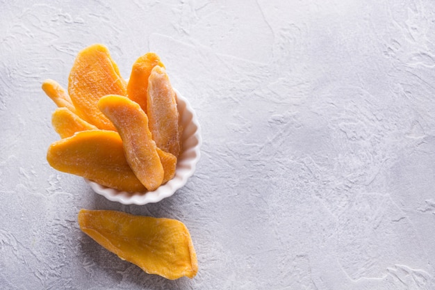 Chips de mango deshidratados y secos en un tazón blanco Cerrar