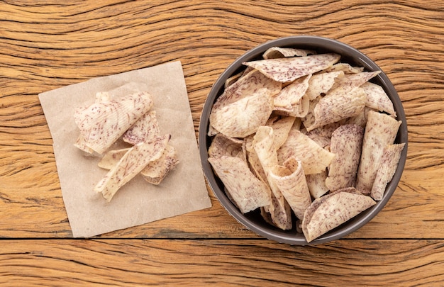 Chips de ñame o taro en un recipiente sobre una mesa de madera