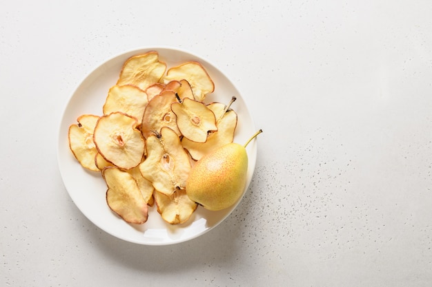 Chips de pera de frutas sobre un fondo blanco. Postre vegano sin azúcar.