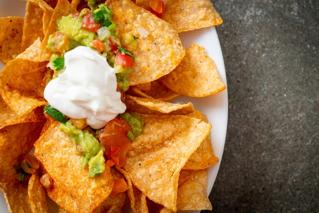 Chips de tortilla de nachos mexicanos con jalapeño, guacamole, salsa de tomate y salsa