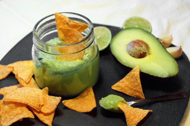 Chips triangulares de nachos con salsa guacamole elaborados a base de aguacate, ajo y lima.