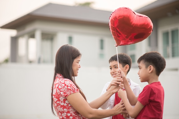 Chiquitos dando corazón de globo a su madre con amor.