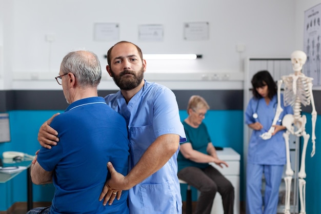 Chiropraktiker, der Wirbelsäulenverletzungen und Rückenschmerzen des alten Mannes für Physiotherapie behandelt. Assistent hilft älteren Patienten mit Verletzungen bei der Genesung und gibt chiropraktische Massagen zur Rehabilitation