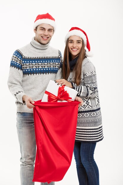 Chirstmas Konzept - junges attraktives Paar mit roter Tasche Sankt, die Chirstmas Tag feiert. Getrennt auf weißem Hintergrund.