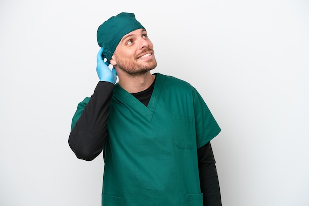 Chirurg, brasilianischer Mann in grüner Uniform, isoliert auf weißem Hintergrund, denkt an eine Idee