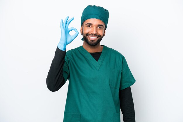 Chirurg Brasilianischer Mann in grüner Uniform isoliert auf weißem Hintergrund mit OK-Zeichen mit den Fingern