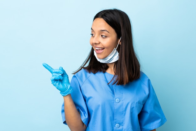 Chirurg Frau über isolierte blaue Wand beabsichtigt, die Lösung zu realisieren, während ein Finger angehoben wird