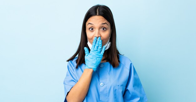 Chirurg Frau über isolierte blaue Wand, die Mund mit Hand bedeckt