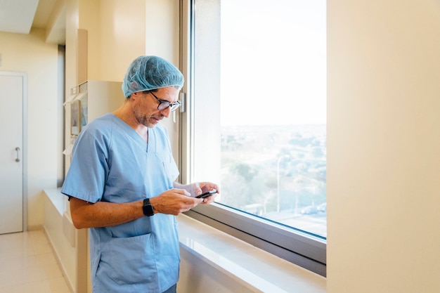 Chirurg mit Smartphone im Operationssaal