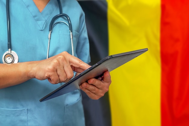 Chirurg oder Arzt, der ein digitales Tablett auf dem Hintergrund der belgischen Flagge verwendet