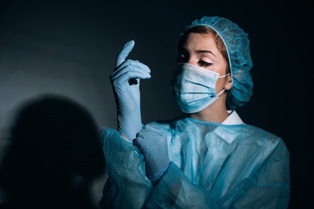 Foto chirurg trägt handschuhe in der dunkelheit