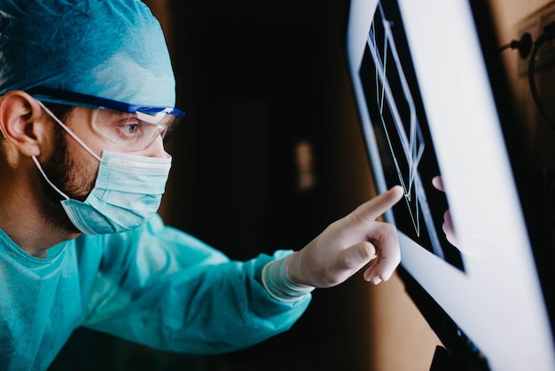 Chirurg untersucht Fluorographiebilder auf einem Monitor in einem Operationssaal einer Arztpraxis