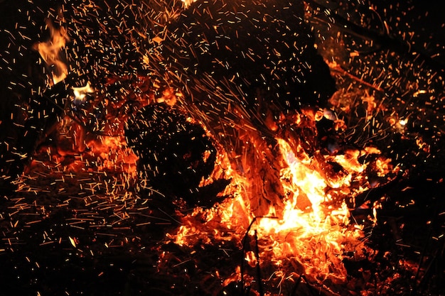 Las chispas ardientes y rojas se elevan de un gran fuego por la noche.