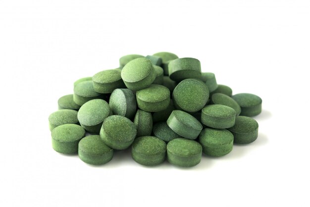 Chlorella o espirulina tabletas en un fondo blanco aislado.