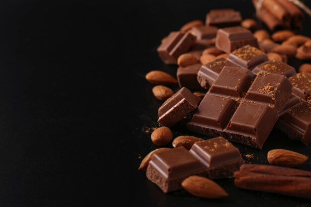 Chocolate con almendras y canela en un primer plano oscuro de la mesa, el enfoque selectivo