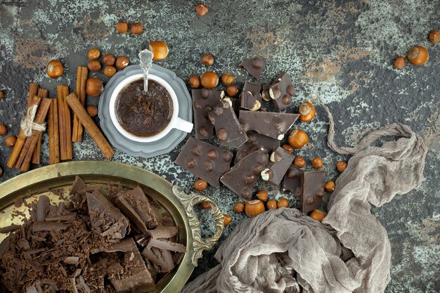 Foto chocolate amargo em uma composição com grãos de cacau e nozes, sobre um fundo antigo.