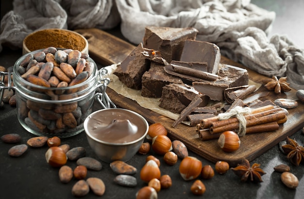 Chocolate amargo em uma composição com grãos de cacau e nozes, sobre um fundo antigo.