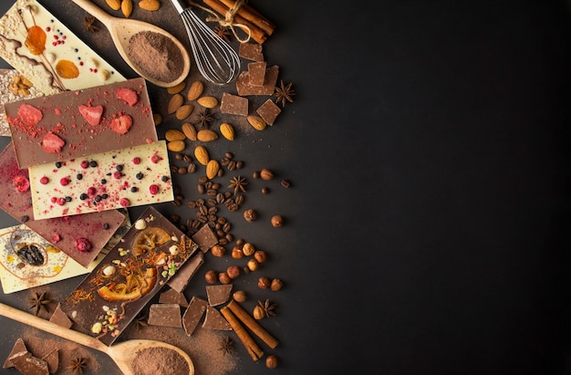 Chocolate artesanal com frutas vermelhas, nozes, frutas secas em um fundo escuro. Chocolate preto e branco. Barra de chocolate. Fundo de chocolate. Receita. Copie o espaço.