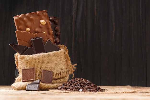 Chocolate en una bolsa de arpillera con chispas de chocolate sobre un fondo de madera