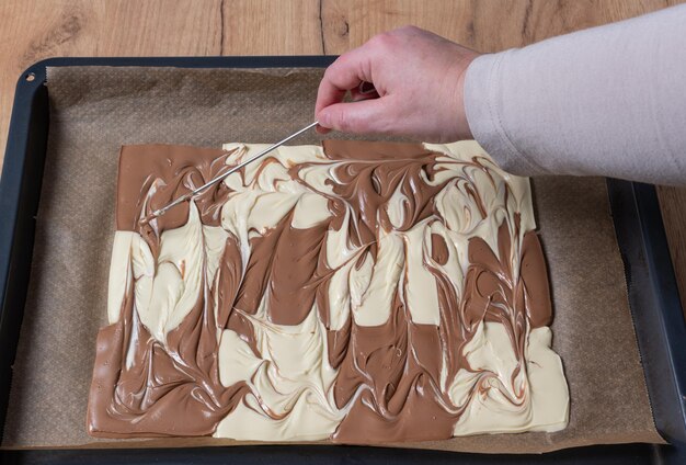 Foto chocolate branco e castanho preparado para um chocolate quebrado coberto com pérolas de açúcar pretzel e nozes