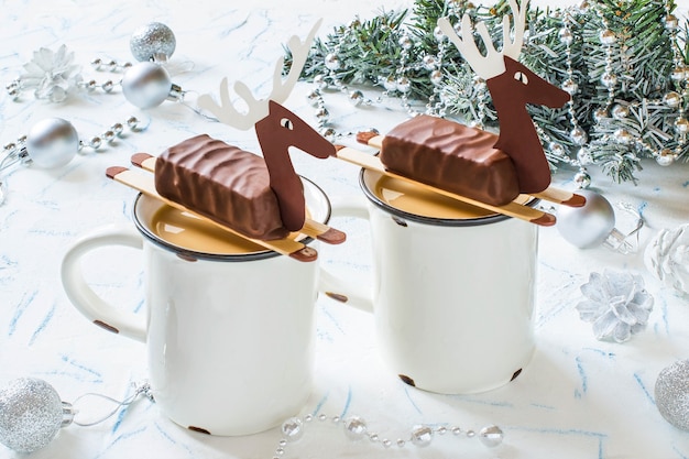 Chocolate caliente con barras de chocolate en forma de ciervo navideño para fiesta navideña infantil