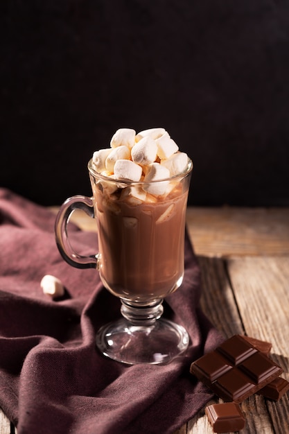 Chocolate caliente con canela y malvavisco sobre fondo de madera