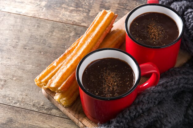 Chocolate caliente con churros en mesa de madera.