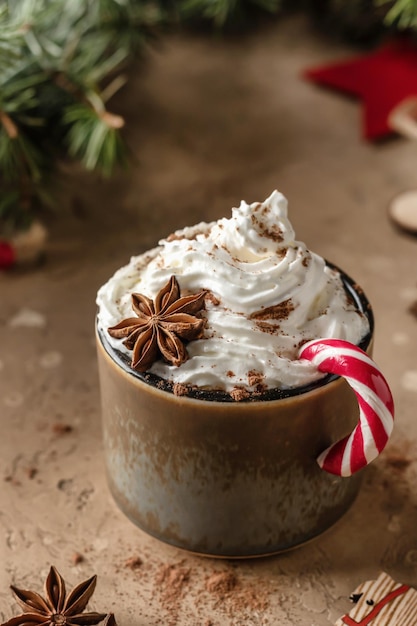 Chocolate caliente con crema batida y caña de caramelo en una mesa marrón festiva