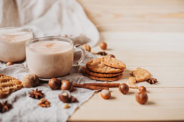 Chocolate caliente con galletas, canela, anís, nueces en la mesa de madera. Vista frontal, copia espacio.