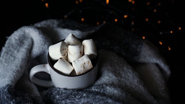 Chocolate caliente con malvavisco en una taza de cerámica blanca. El concepto de vacaciones acogedoras y año nuevo.