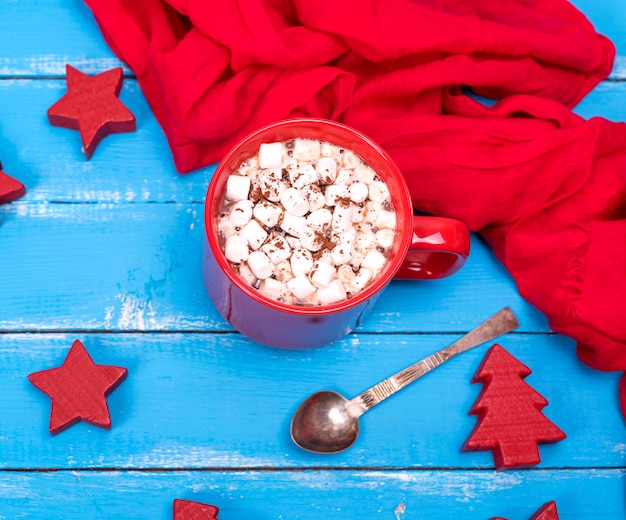 Chocolate caliente con malvaviscos en una taza de cerámica roja.