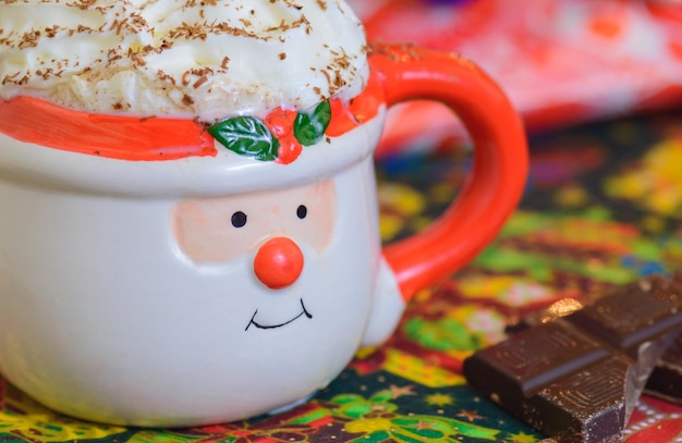 Chocolate caliente de Navidad en la taza de Santa con crema batida y chocolate afeitado