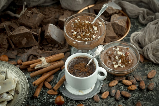 Chocolate caliente sobre un fondo antiguo en una composición con cacao en grano y nueces.