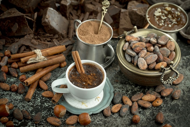 Chocolate caliente sobre un fondo antiguo en una composición con cacao en grano y nueces.