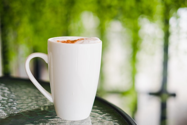 Chocolate caliente en la taza blanca en la tabla de cristal por mañana.