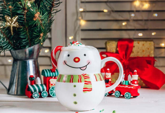 Chocolate caliente en taza sonriente muñeco de nieve en Navidad. Enfoque selectivo