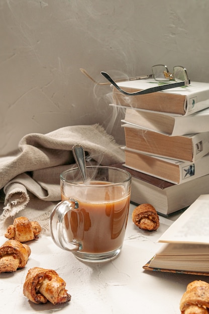 Chocolate caliente en una taza de vidrio transparente. Muy cerca hay panecillos caseros con nueces.