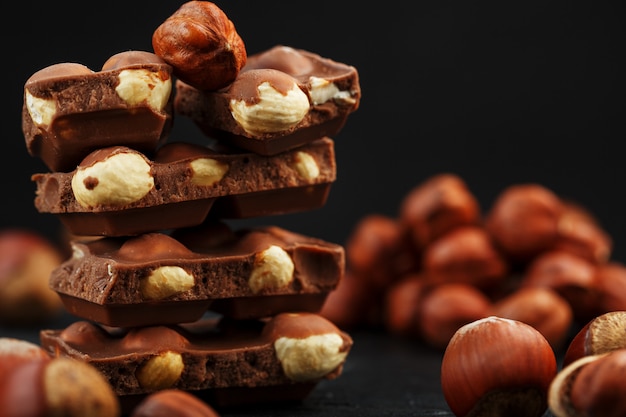 Chocolate com avelãs em forma de torre, rodeado de nozes com casca e descascado.