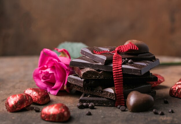 Chocolate com fita, rosa e coração no amor do dia de São Valentim.