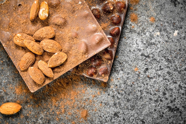 Chocolate com nozes e cacau em pó na mesa rústica.