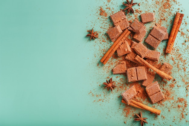 Chocolate de leite com especiarias e cacau em uma superfície verde