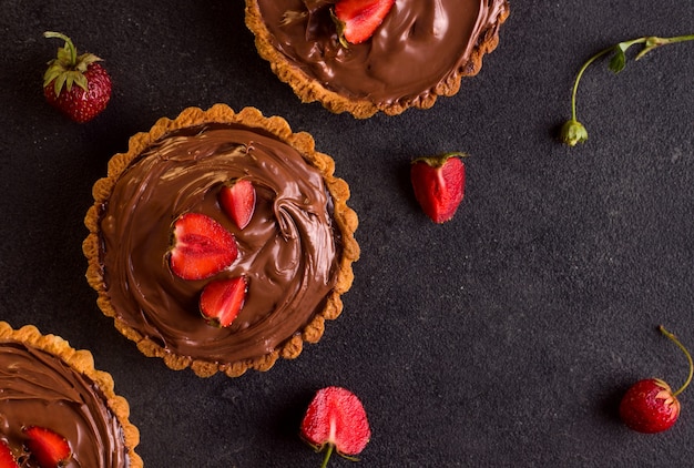 Chocolate de torta de sobremesa com morangos em um fundo preto. Vista de cima. Copie o espaço