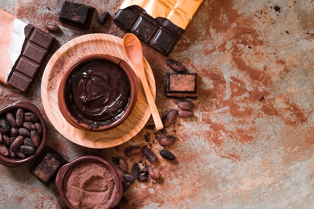 Foto chocolate derretido y barra de chocolate hecha con granos de cacao en la mesa