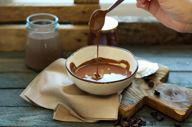 Foto chocolate derretido en un cuenco de vidrio sobre un fondo de madera