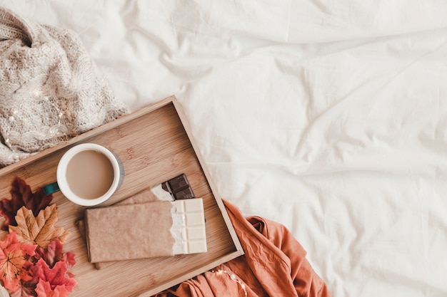 Chocolate e folhas perto de café na cama